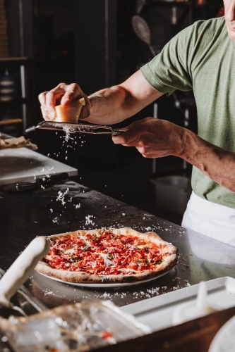 grating cheese over pizza